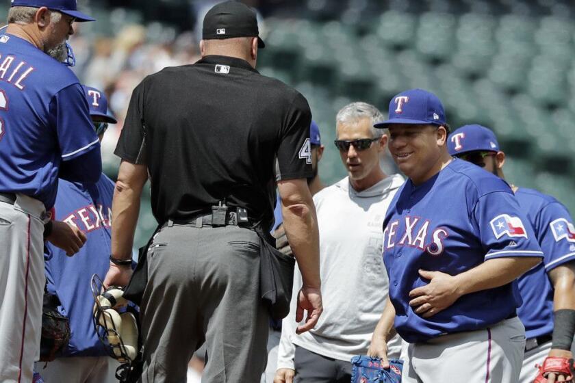 Texas Rangers starting pitcher Bartolo Colon, second from right, smiles as he rubs his stomach and returns to the mound after talking with a Rangers trainer after Colon was hit by a ball hit by Seattle Mariners' Jean Segura during the fourth inning of a baseball game Wednesday, May 16, 2018, in Seattle. The Rangers won 5-1. (AP Photo/Ted S. Warren)