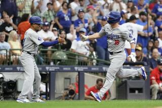 Los Angeles Dodgers' Will Smith is congratulated by third base coach Dino Ebel after hitting a solo home run during the second inning of a baseball game against the Milwaukee Brewers, Tuesday, Aug. 13, 2024, in Milwaukee. (AP Photo/Aaron Gash)