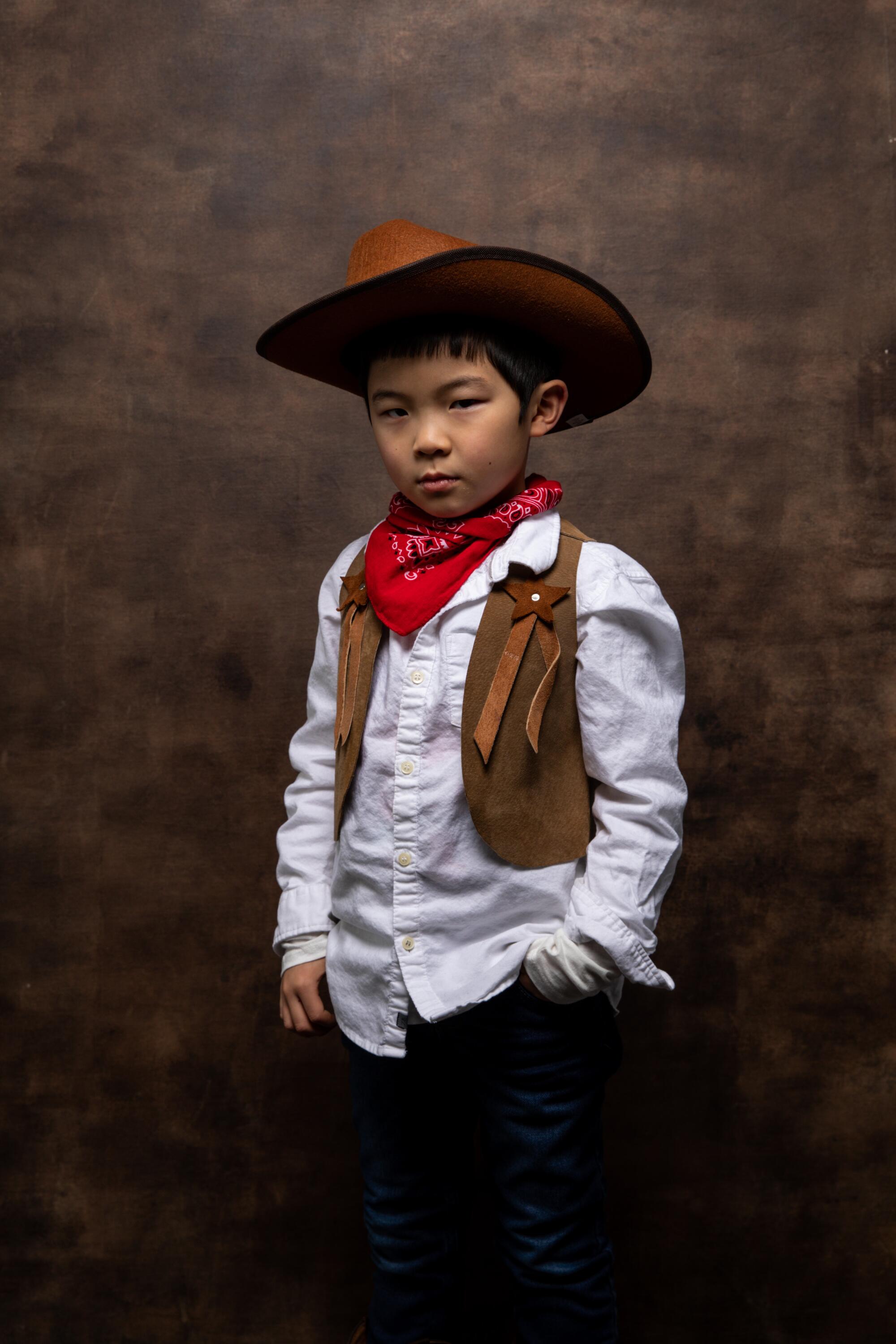 Alan Kim, in a cowboy costume, stands sideways, projecting some movie-western realness.