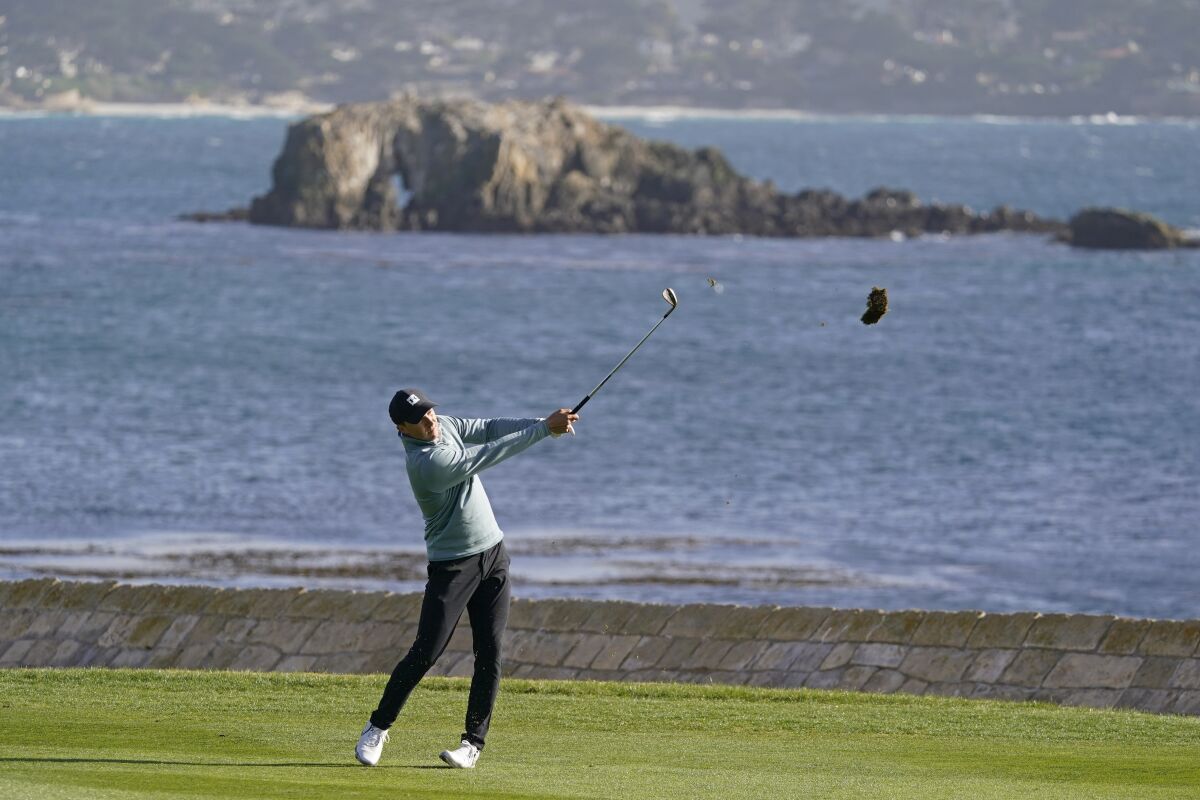 Jordan Spieth hits his approach shot to the 18th green at Pebble Beach Golf Links on Feb. 13, 2021.