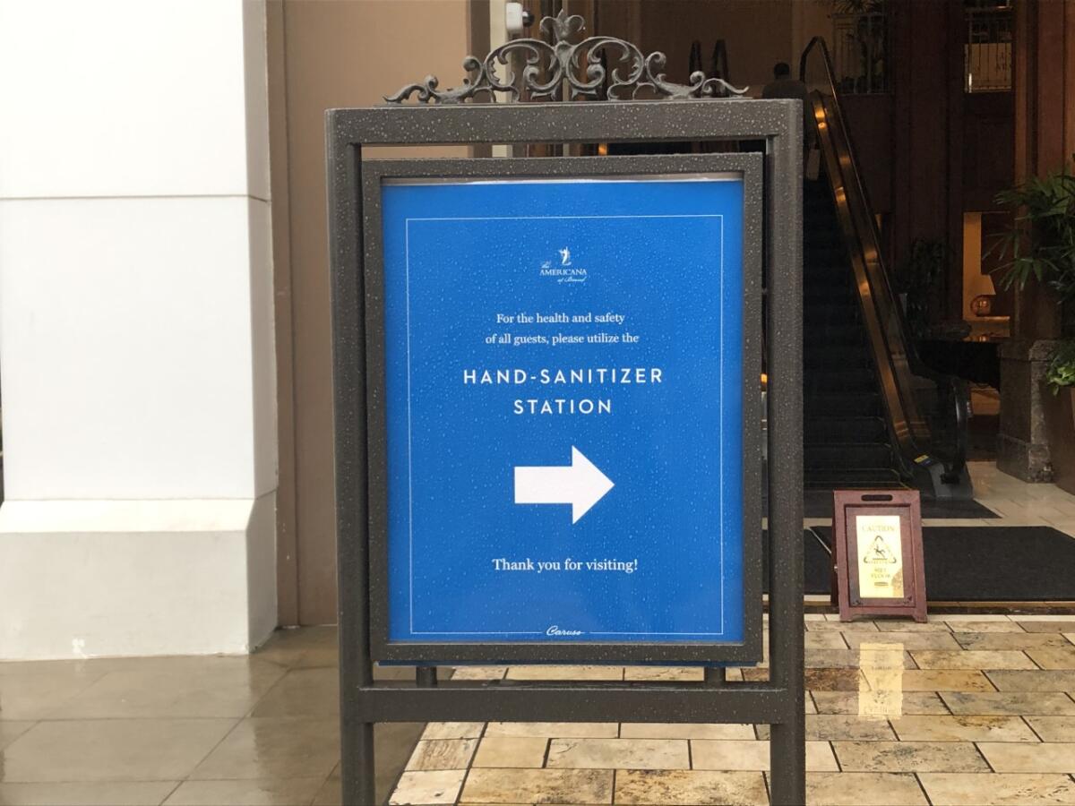 A sign directs mall visitors to hand-sanitizer station.