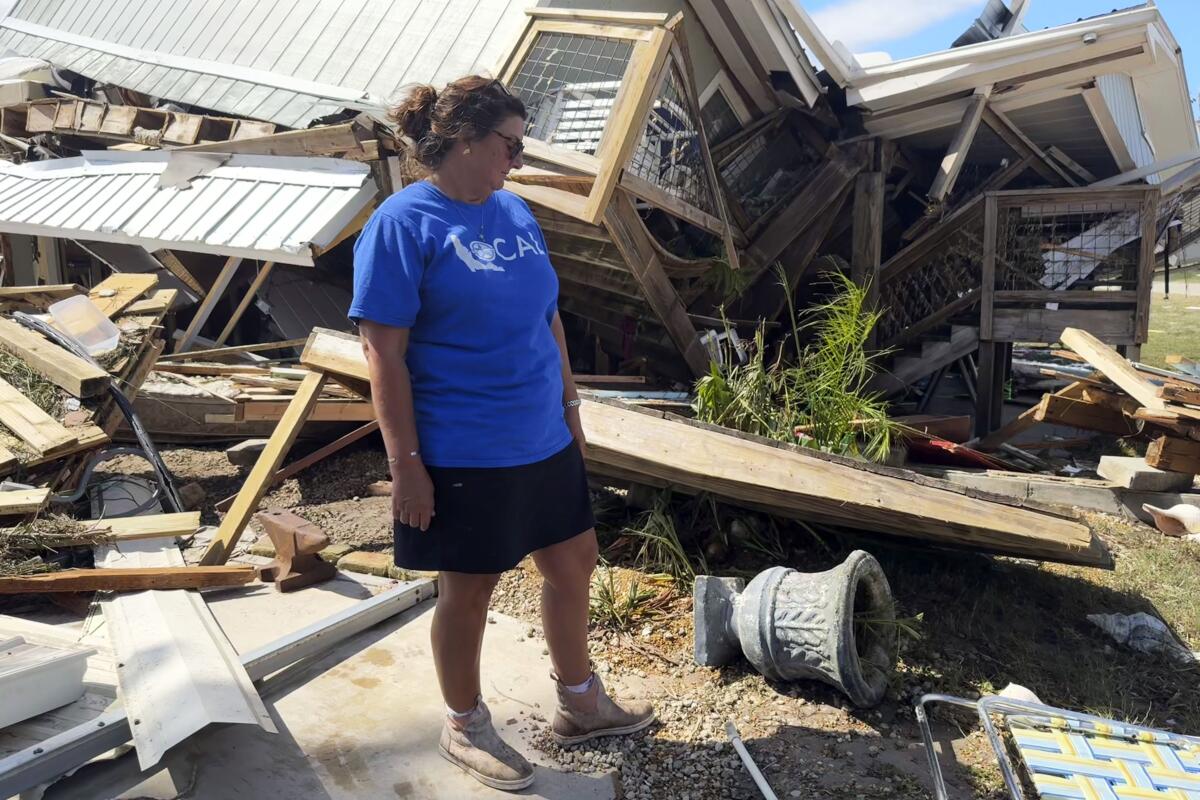 A woman stands amid the wreckage of her home.