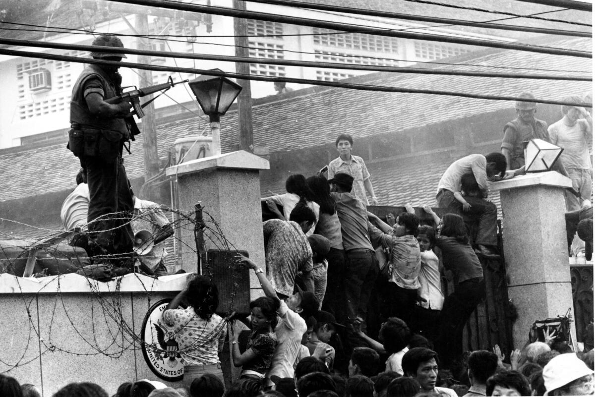 Vietnamese people scale the U.S. embassy wall in Saigon on April 29, 1975.