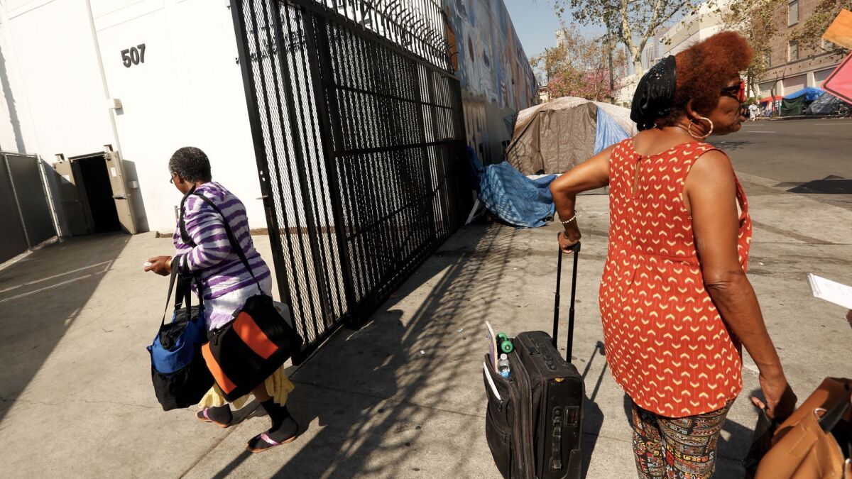 People carry their belongings in and out of a storage facility for the homeless population on skid row.