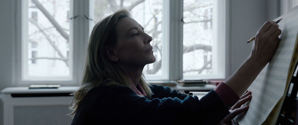 Cate Blanchett sits at a piano writing notes on sheet music in a scene from "Tar."