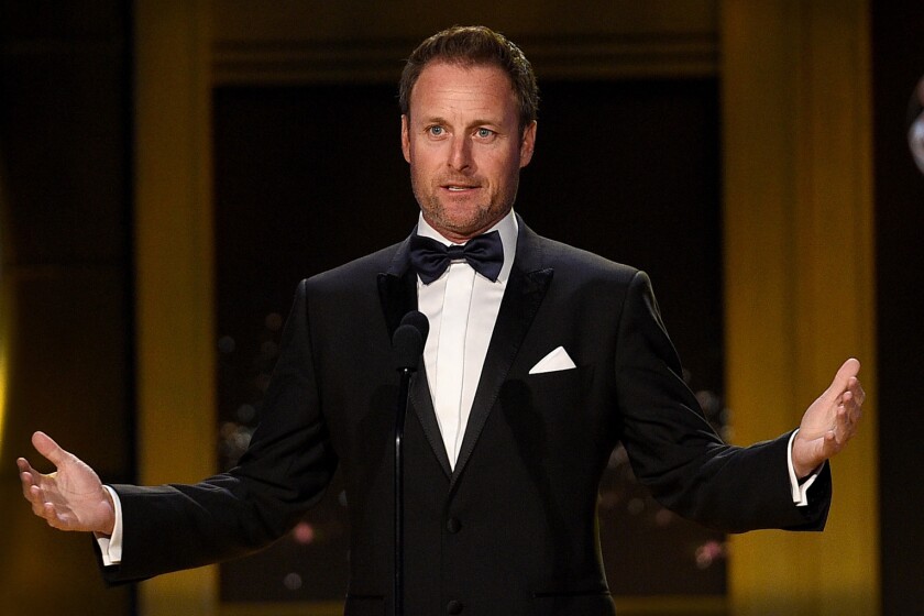 Chris Harrison in a tuxedo at a microphone