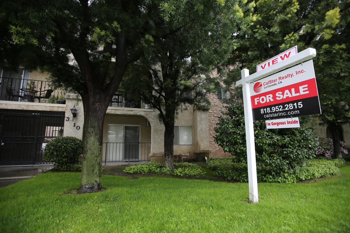 A for-sale sign hangs in front of a condo complex