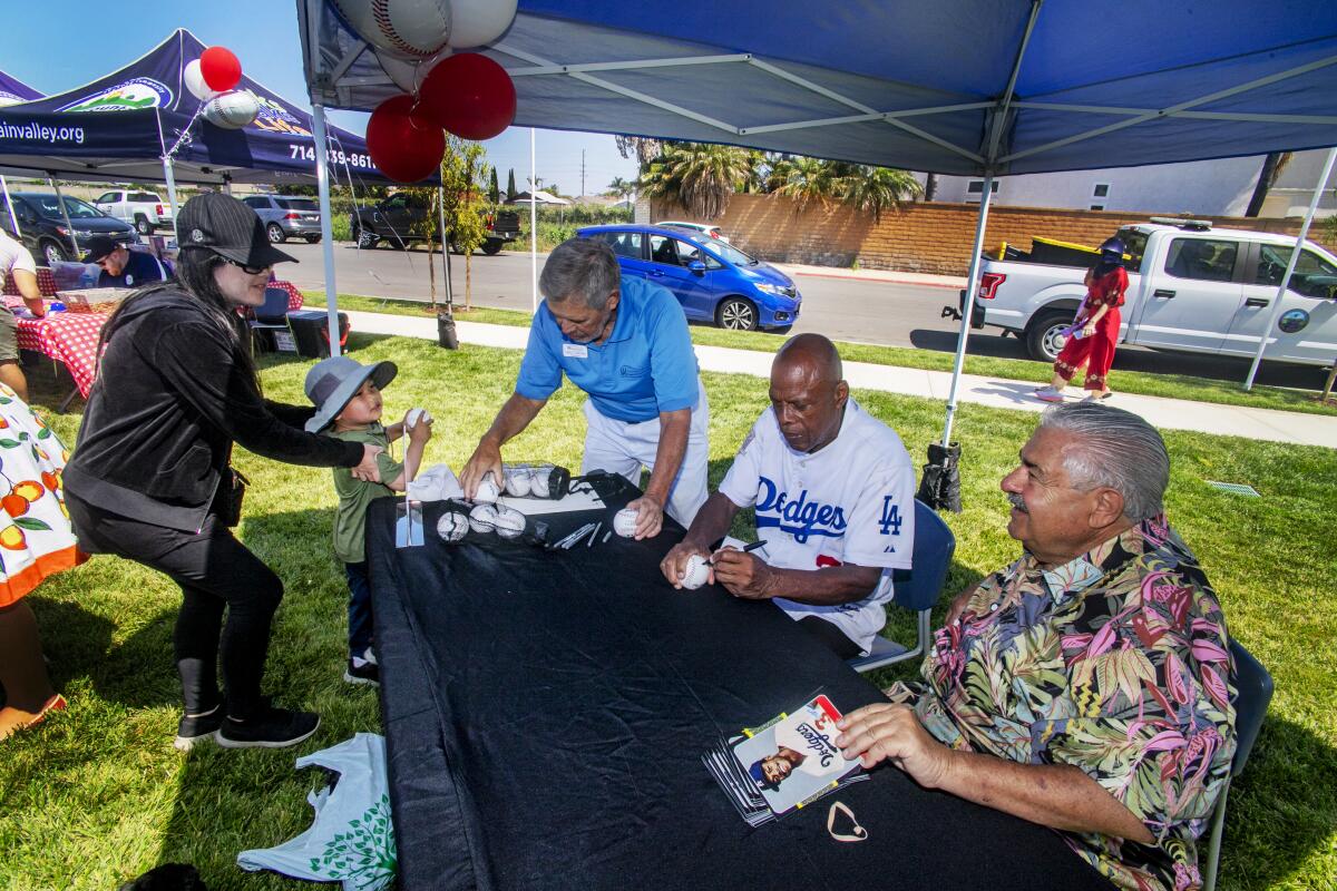 Former Dodgers player Rudy Law autographs a baseball for 4-year-old Mike Hung.
