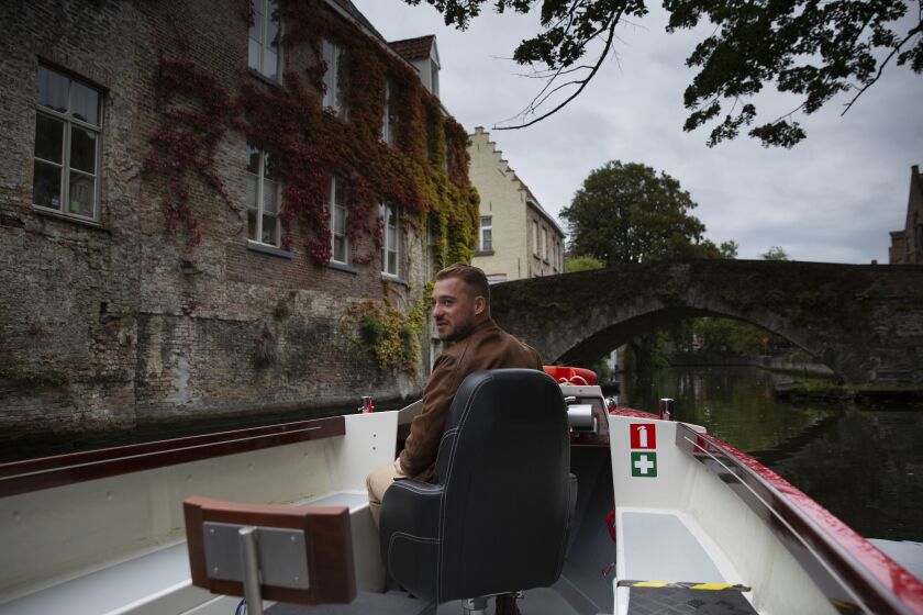 Fourth generation tour boat operator Michiel Michielsens drives his electric boat down a canal in Bruges, Belgium, Wednesday, Sept. 2, 2020. Europe’s leanest summer tourist season in history is starting to draw to a close, six months after the coronavirus hit the continent. COVID-19 might tighten its grip over the coming months, with losses piling up in the tens of billions of euros across the 27-nation European Union. In the Belgian city of Bruges, white swans instead of tourist boats rule the canals, hotels stand empty and museums count their losses. (AP Photo/Virginia Mayo)