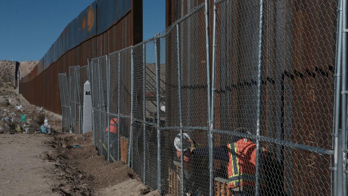 Workers this month extend the height of the border fence separating the towns of Anapra, Mexico, and Sunland Park, New Mexico.