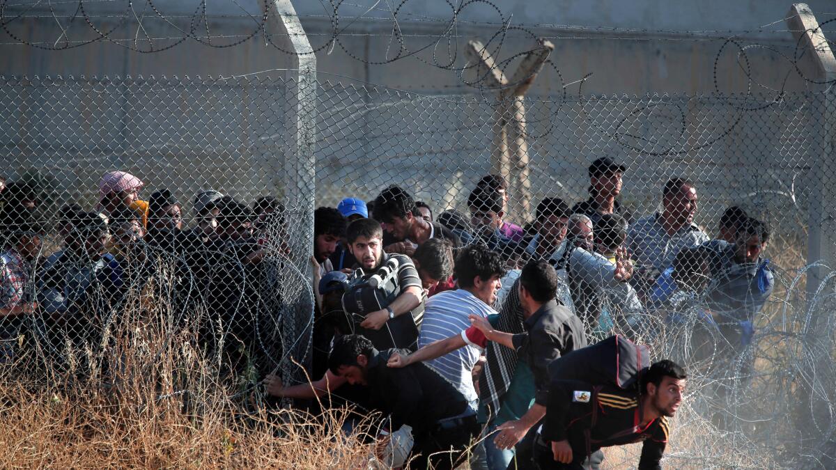 Syrian refugees burst into Turkey after breaking through a border fence and crossing the boundary separating the two countries in this June 14, 2015 photo. Turkey has been building a concrete wall along parts of the border in recent years.