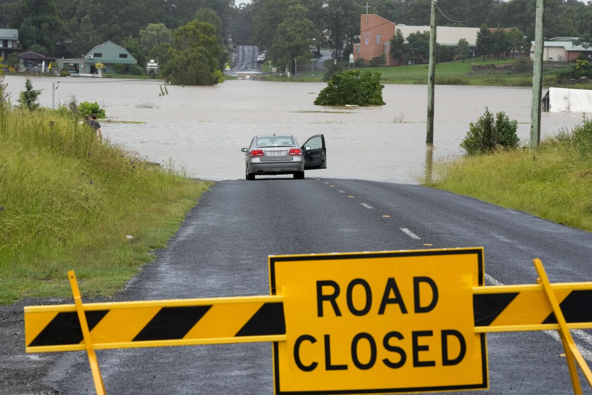 A car is parked near a flooded road at Windsor on the outskirts of Sydney, Australia, Thursday, March 3, 2022.Tens of thousands of people had been ordered to evacuate their homes and many more had been told to prepare to flee as parts of Australia's southeast coast are inundated by the worst flooding in decades. (AP Photo/Rick Rycroft)