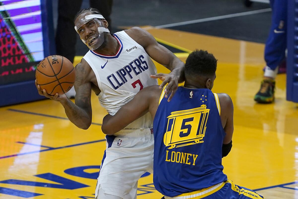 Clippers forward Kawhi Leonard is fouled by Warriors forward Kevon Looney.