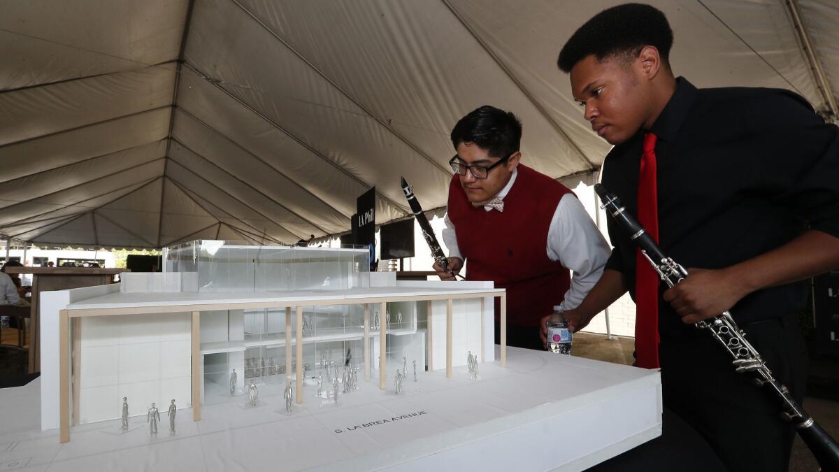 Edson Nazareno, left, and Dameon Williams, both graduates of the Youth Orchestra Los Angeles program, look at the model for YOLA's future home in Inglewood.