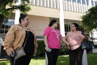 three women stand outside speaking to the press about their court hearing