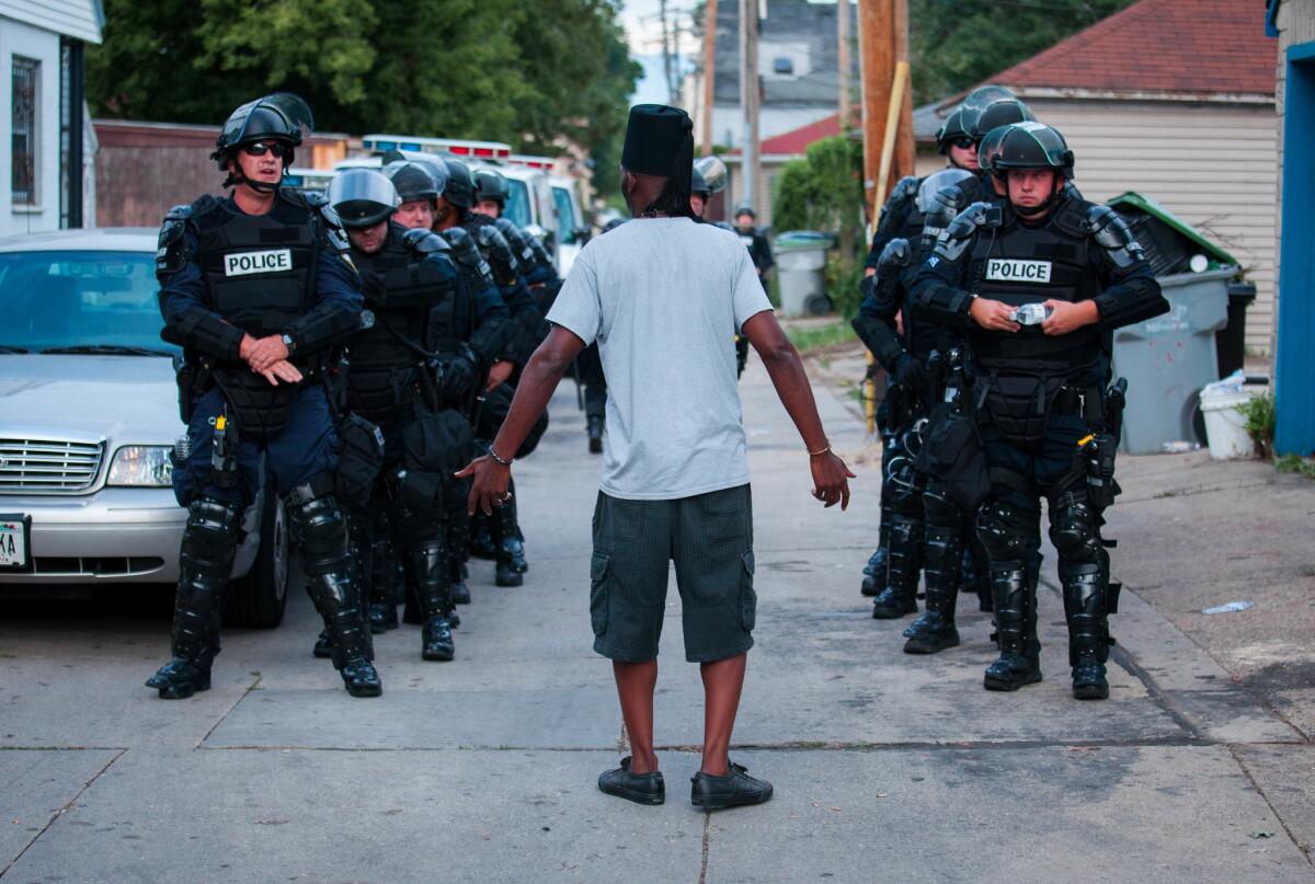A man talks to police in riot gear as they wait in an alley after a second night of clashes between protestors and police Aug. 15, 2016, in Milwaukee, Wisconsin.