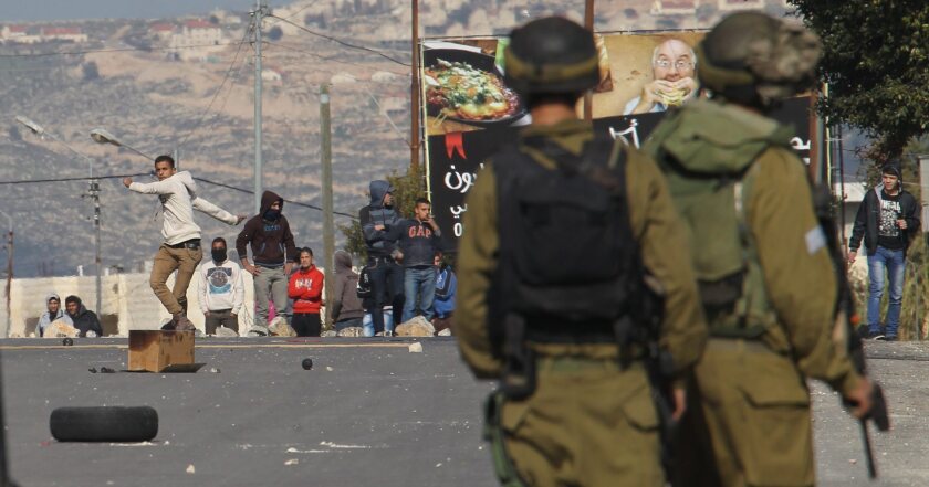 Palestinian demonstrators hurl stones at Israeli soldiers on Wednesday during clashes at the Huwwara checkpoint near Nablus in the West Bank.