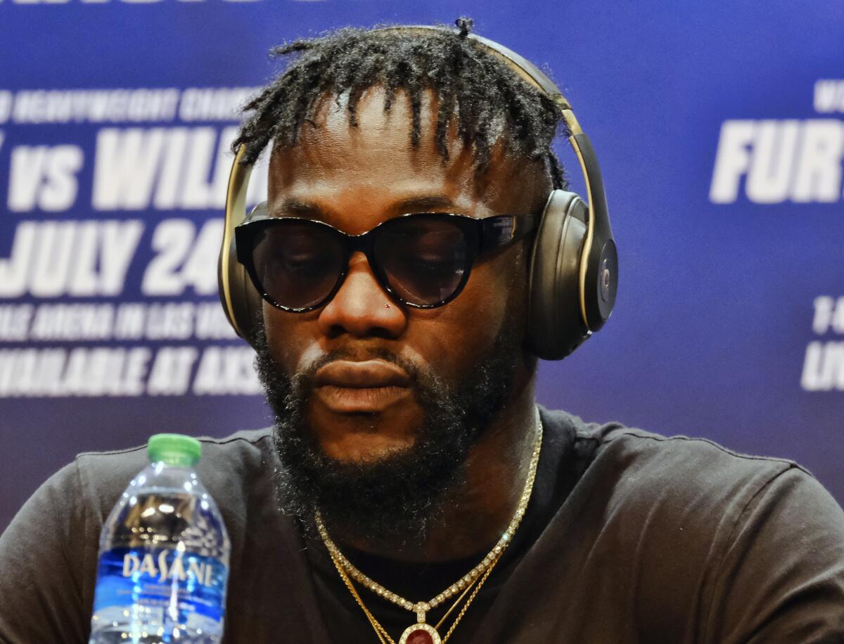 Longtime heavyweight champion Deontay Wilder wears headphones and refuses to answer questions during a news conference