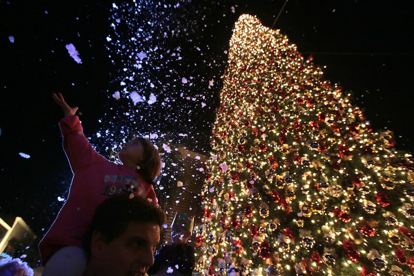 Lily Glasser, 4, reaches out for faux snow at the annual Christmas tree lighting ceremony at Fashion Island in Newport Beach.