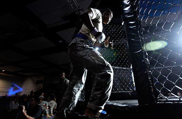 Staff Sgt. Jackelyn Walker enters the ring to fight Pfc. Gregory Langarica in the bantamweight championship of the finals of the Ft. Hood Combative Championships in Killeen, Texas, on Feb. 16. Langarica won the fight when it was called off in the second round. Walker had to be carried off on a stretcher. Fights during the finals take place in a cage with advanced rules. The Army still doesn't allow women to fight in combat but does let them fight against male soldiers at mixed martial arts tournaments at Army bases all around the country.