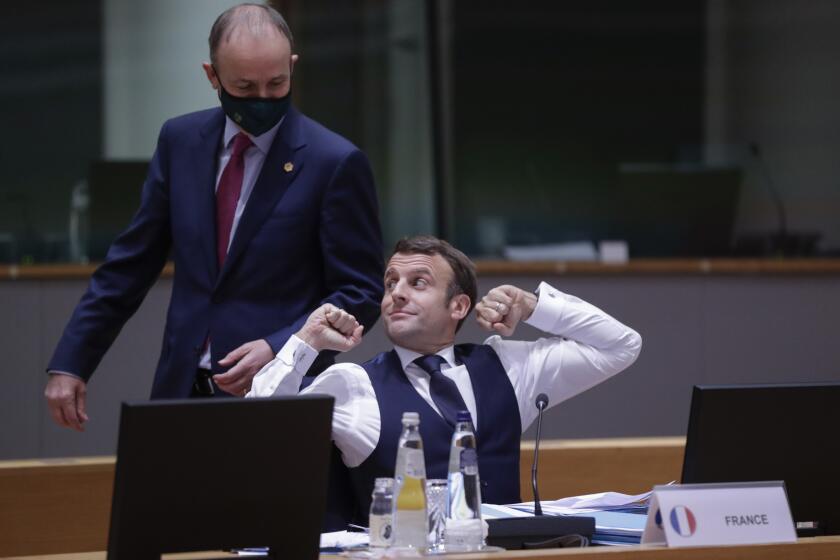 French President Emmanuel Macron stretches Friday after an all-night negotiating session at an EU summit in Brussels.