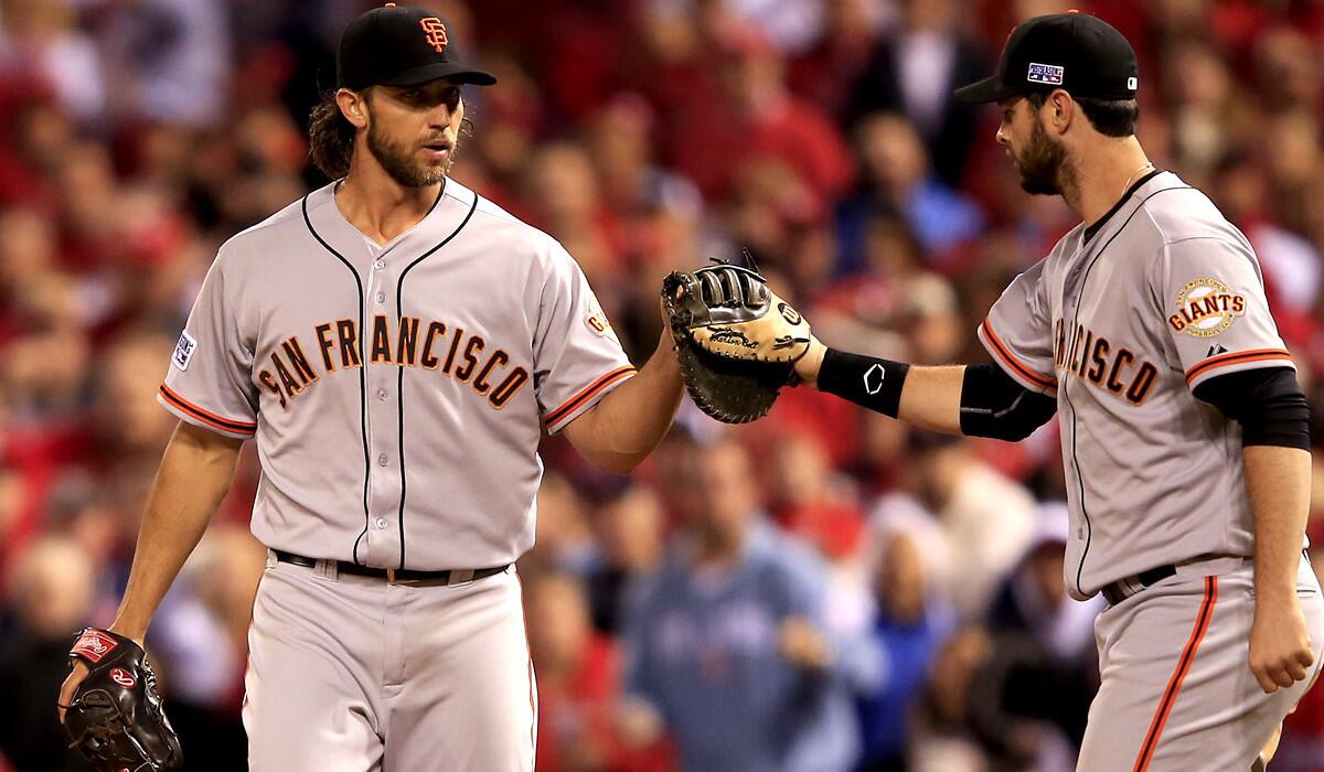 Giants pitcher Madison Bumgarner, left, is congratulated by first baseman Brandon Belt after tagging out a Cardinals batter at first base in the seventh inning of Game 1 in the NLCS on Saturday.
