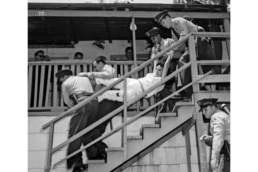 May 8, 1959: Aurora Vargas is carried by Los Angeles County Sheriffs during eviction from house in Chavez Ravine. Photo was taken by Los Angeles Mirror-News photographer Hugh Arnott.