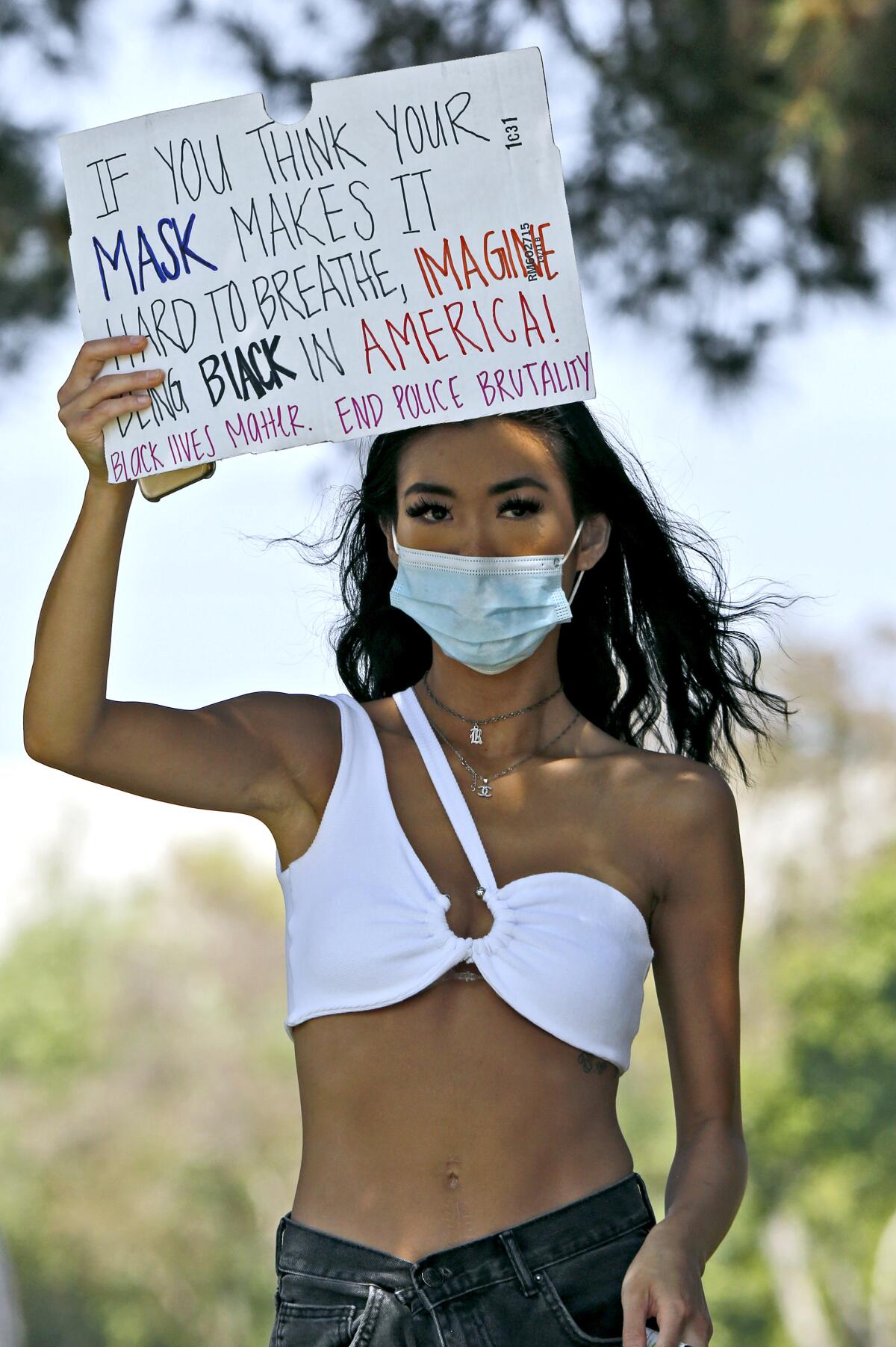 Newport Beach resident Rachel Han, 22, holds a sign up during a Black Lives Matter rally at Bonita Creek Park on Saturday