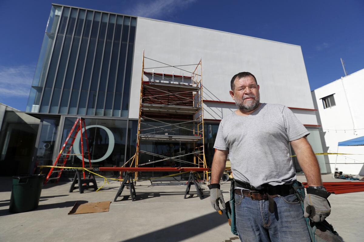 Before: Artist Marcos Ramirez, known as "ERRE," installing "Of Fence," meant to evoke a border wall, on the Oceanside Museum of Art.