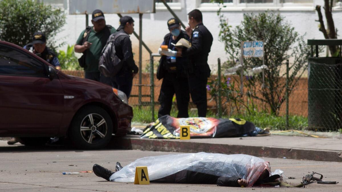 Two bodies, one identified as a prison guard, lie covered outside the Roosevelt Hospital in Guatemala City after Wednesday's attack.