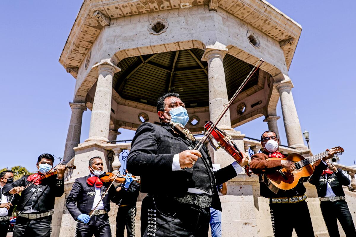Mariachi musicians perform around an freestanding bandstand.