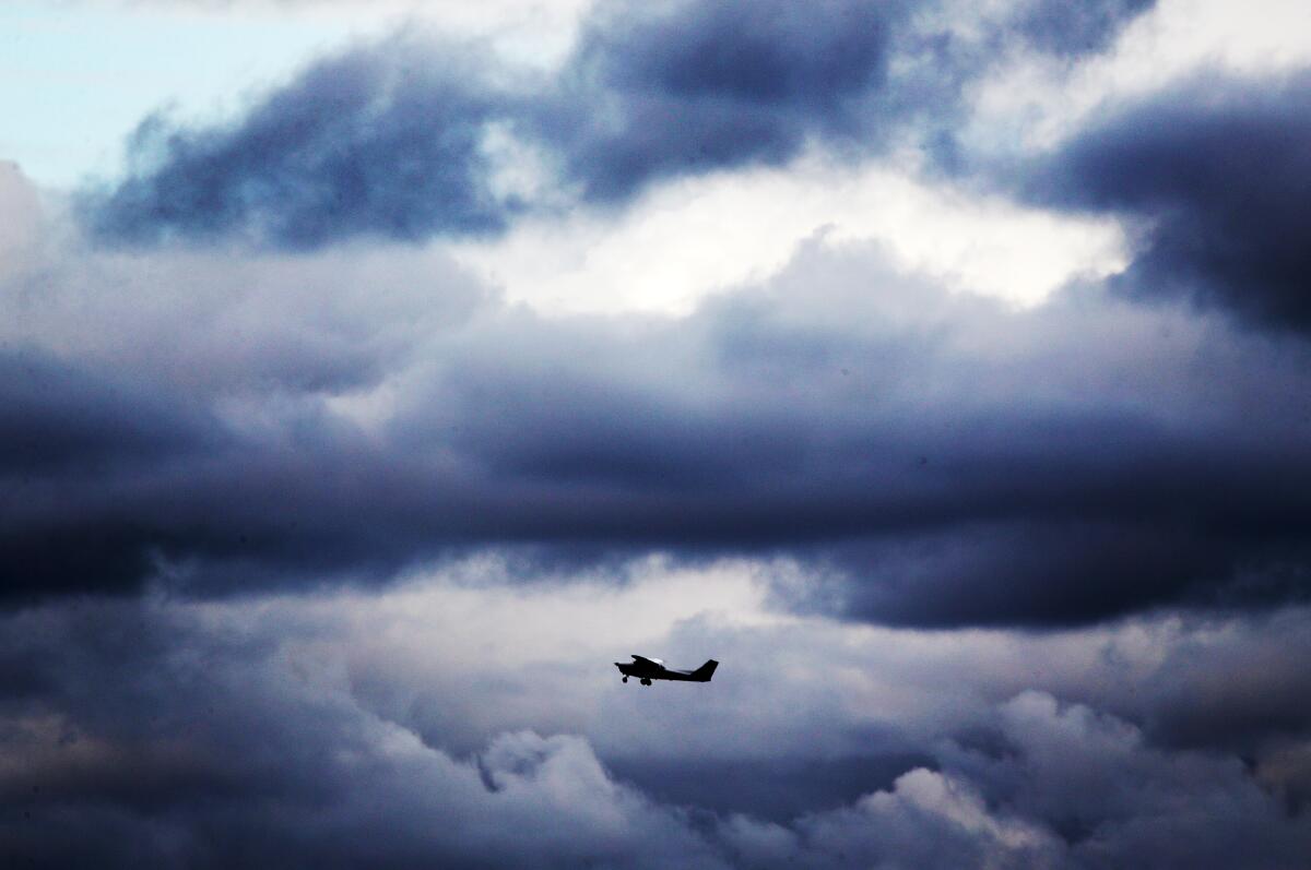 A plane takes off from the Long Beach Airport under heavy clouds 