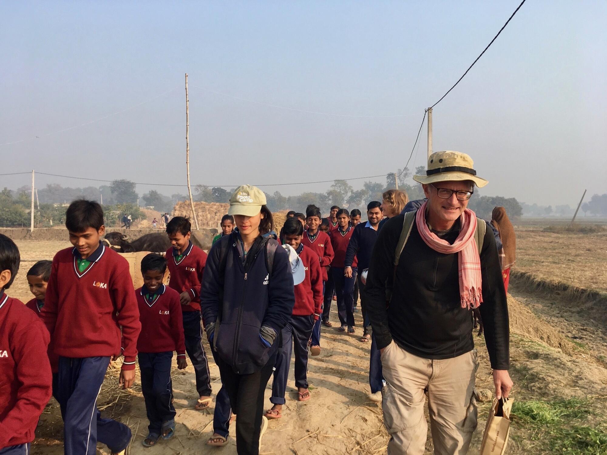 Paul Salopek walks with students in red jumpers while visiting a school in Bihar, India. 