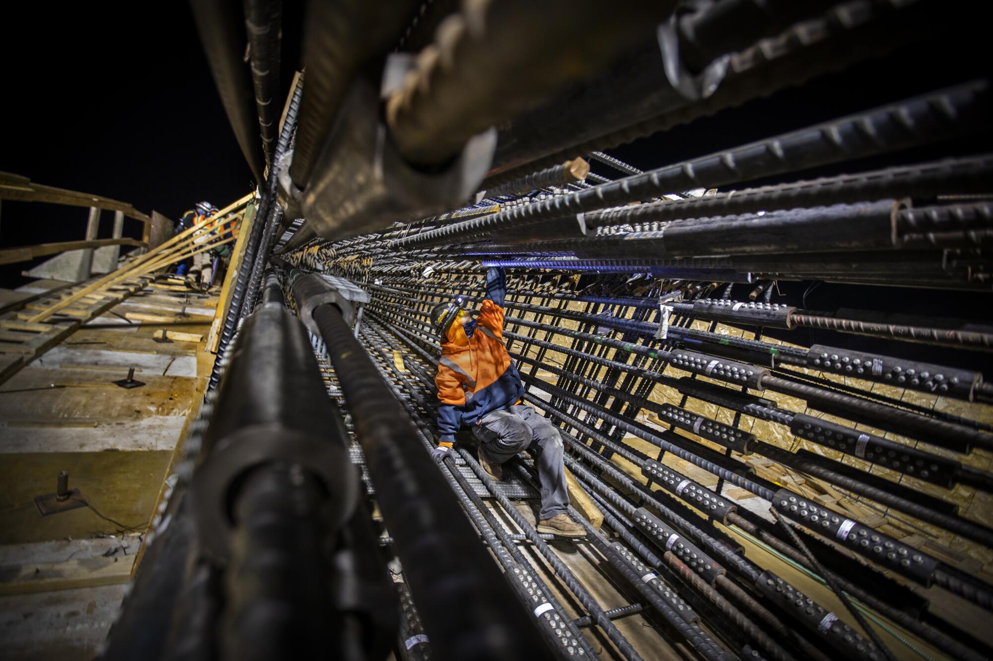 A construction worker climbs down an arch framework of reinforcing rods