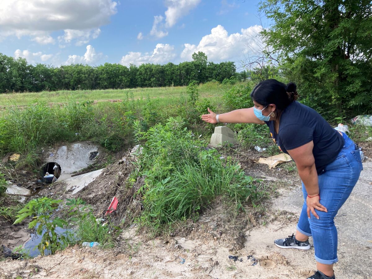 FILE - Shirley Ronquillo, a Houston area community activist, points to an open drainage ditch that is blocked by debris and trash May 27, 2021, in Houston. The ditch is located near a subdivision in an unincorporated part of Harris County that has a history of flooding. The U.S. Department of Housing and Urban Development says Texas' administration of flood relief money from Hurricane Harvey broke federal law by discriminating against Black and Hispanic residents of the Houston area. The federal agency's decision could channel millions of dollars of aid to communities battered by the 2017 storm. (AP Photo/Juan A. Lozano File)