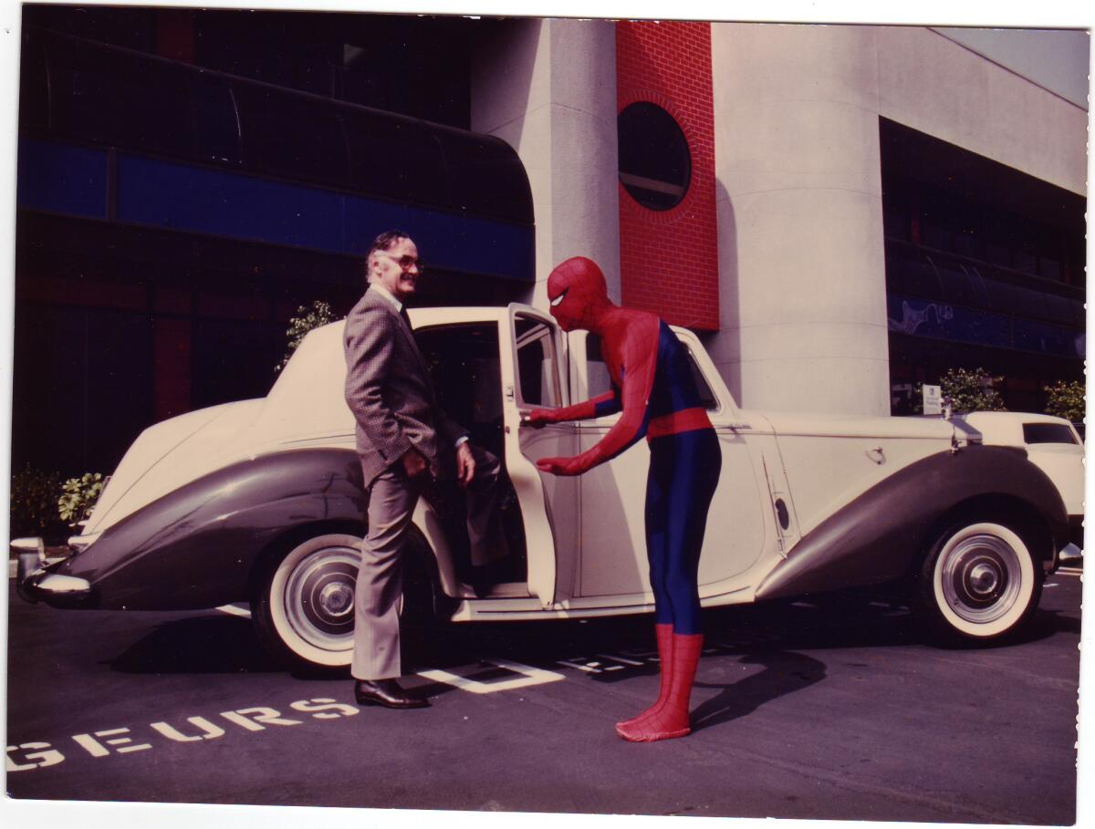 Spider-Man holds a car door open for Stan Lee.