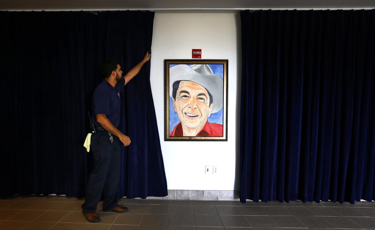 Maintenance worker Danny Alvarez pulls a curtain in preparation for Wednesday's GOP debate at the Ronald Reagan Presidential Library in Simi Valley.