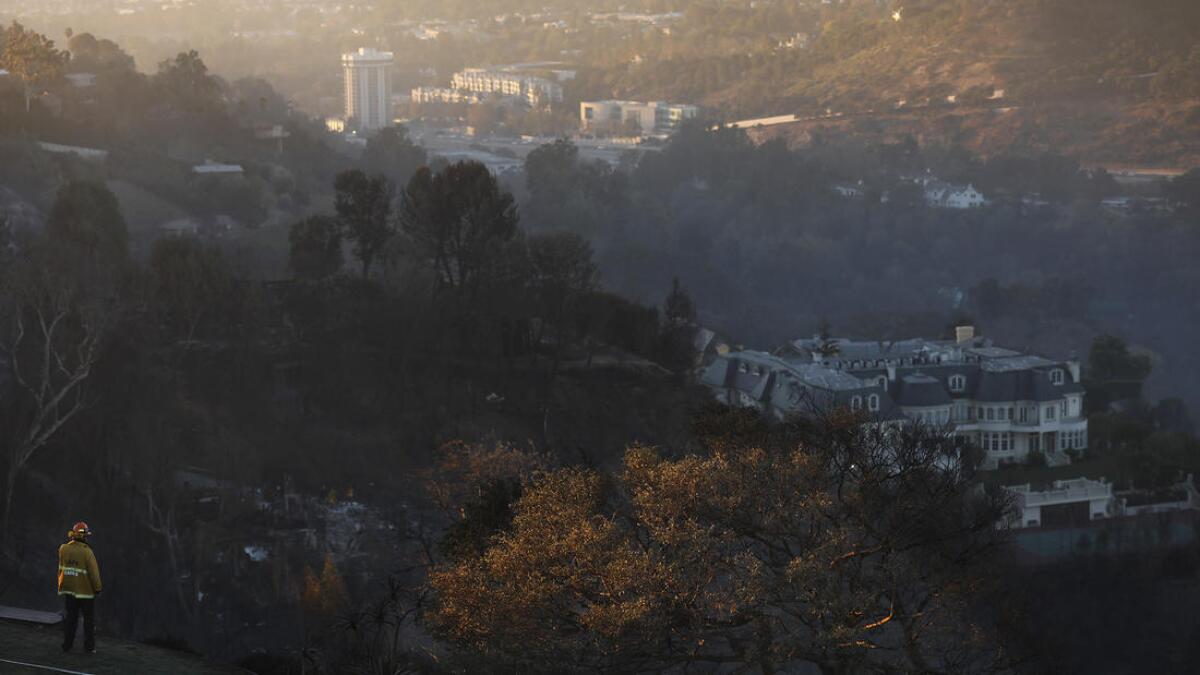 A firefighter monitors the scene over Bel-Air, where the Skirball fire has destroyed several homes.