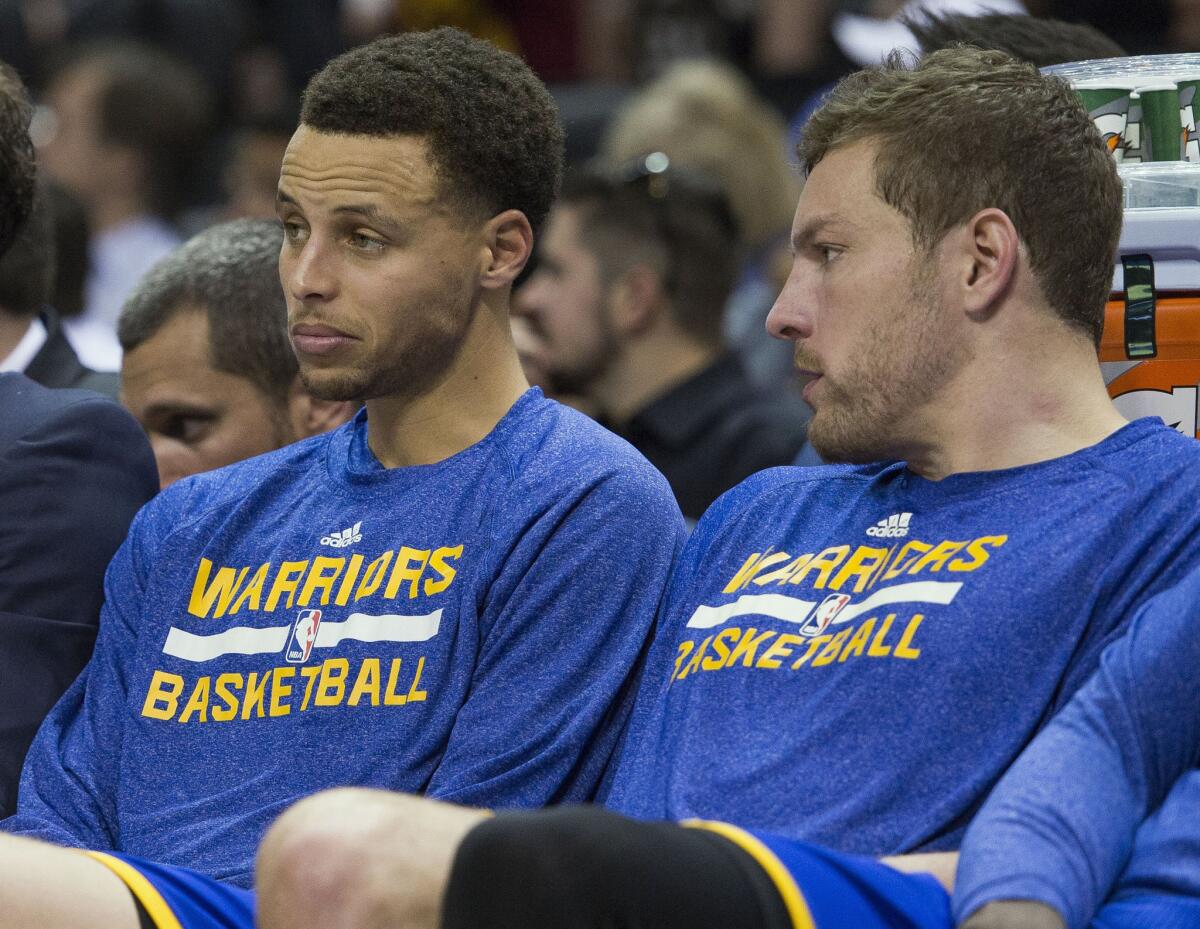 Warriors guard Stephen Curry and forward David Lee sit on the bench during the second half of the Warriors' 107-92 loss to the Spurs.