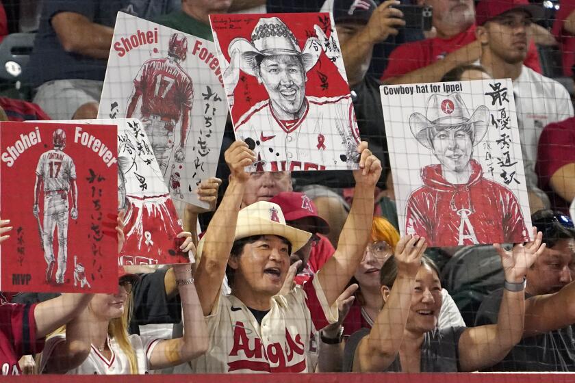 Fans hold up pictures of Los Angeles Angels' Shohei Ohtani and his interpreter Ippei Mizuhara.