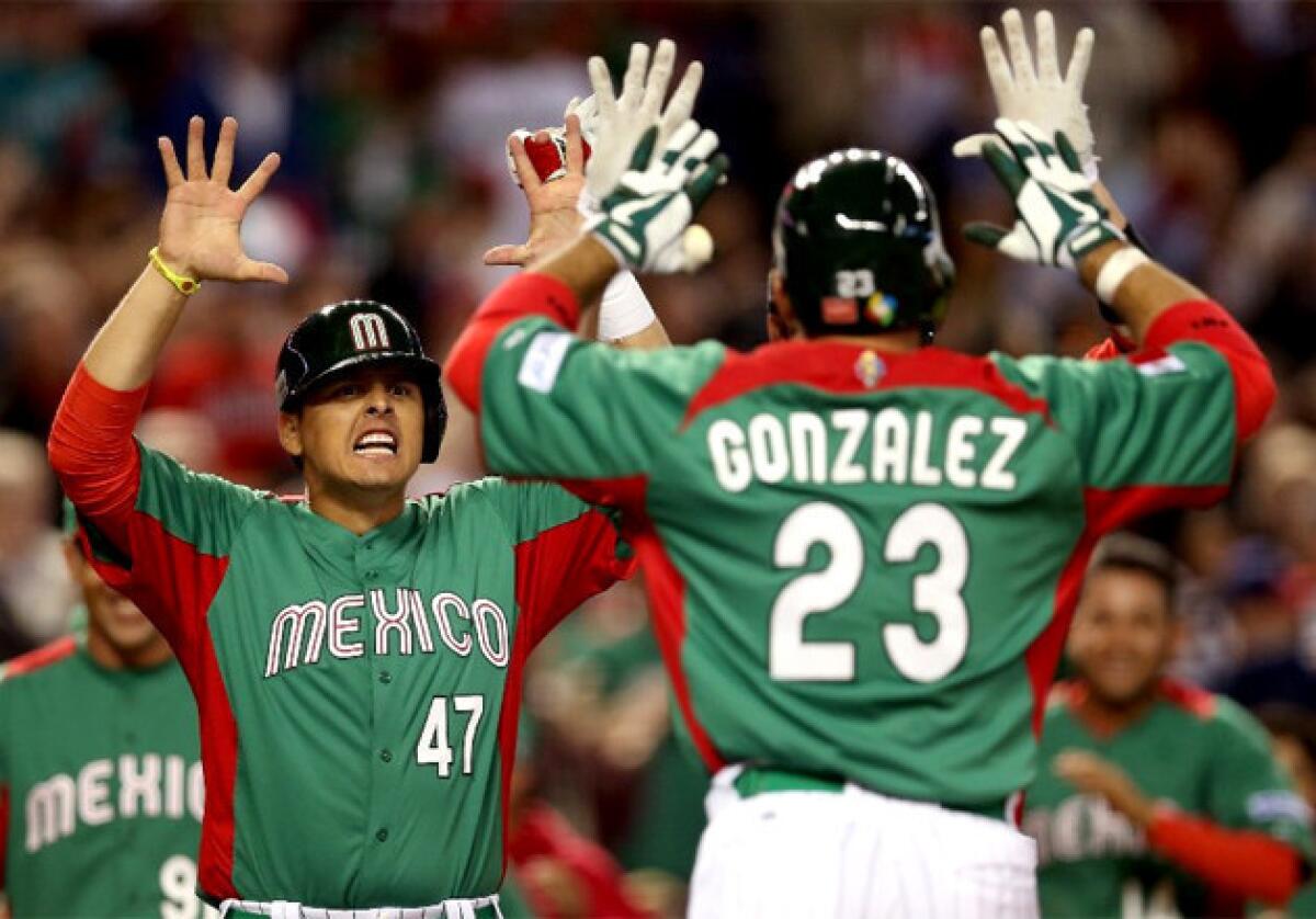 Luis Cruz and Adrian Gonzalez celebrate after Gonzalez's two-run home run against the U.S.