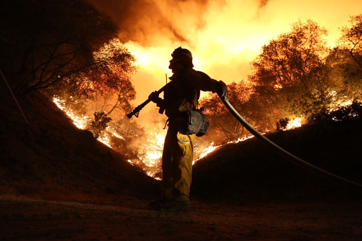 Andrew Dodds mans the water line as firefighters work to start a backfire to contain the Butte fire on Fricot City Road near Sheeps Ranch, Calif., on Sept. 12.