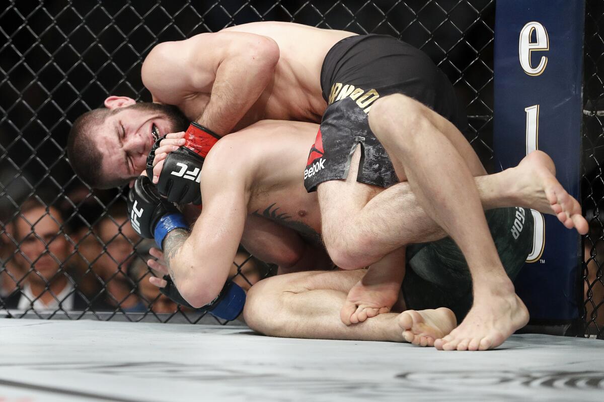 Khabib Nurmagomedov, top, applies a rear naked choke hold to Conor McGregor during a lightweight title mixed martial arts bout at UFC 229 in Las Vegas, Saturday, Oct. 6, 2018. Nurmagomedov won the fight by submission during the fourth round to retain the title.