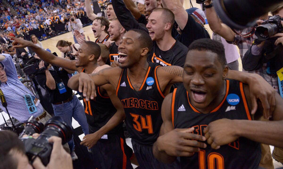 Mercer's Langston Hall, left, Jibri Bryan, center, and Ike Nwamu celebrate with fans following their 78-71 upset victory over third-seeded Duke in the NCAA tournament Friday.