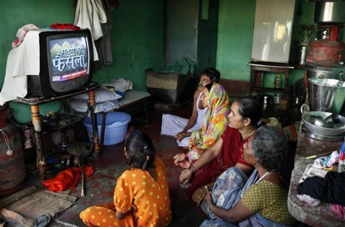 An Indian family watches television as they await news on the Ayodhya verdict, Thursday, Sept. 30, 2010, in Ayodhya, India. An Indian court has ruled that a disputed holy site in the town of Ayodhya should be split between the Hindu and Muslim communities. The conflict over the site has set off bloody communal riots in the past and India has sent hundreds of thousands of troops into the streets to keep order. (AP Photo/Rajesh Kumar Singh)