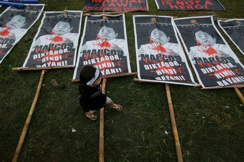 A Filipino boy walks beside posters with pictures of dictator Ferdinand Marcos during a rally Nov. 25 at Manila's Rizal Park.