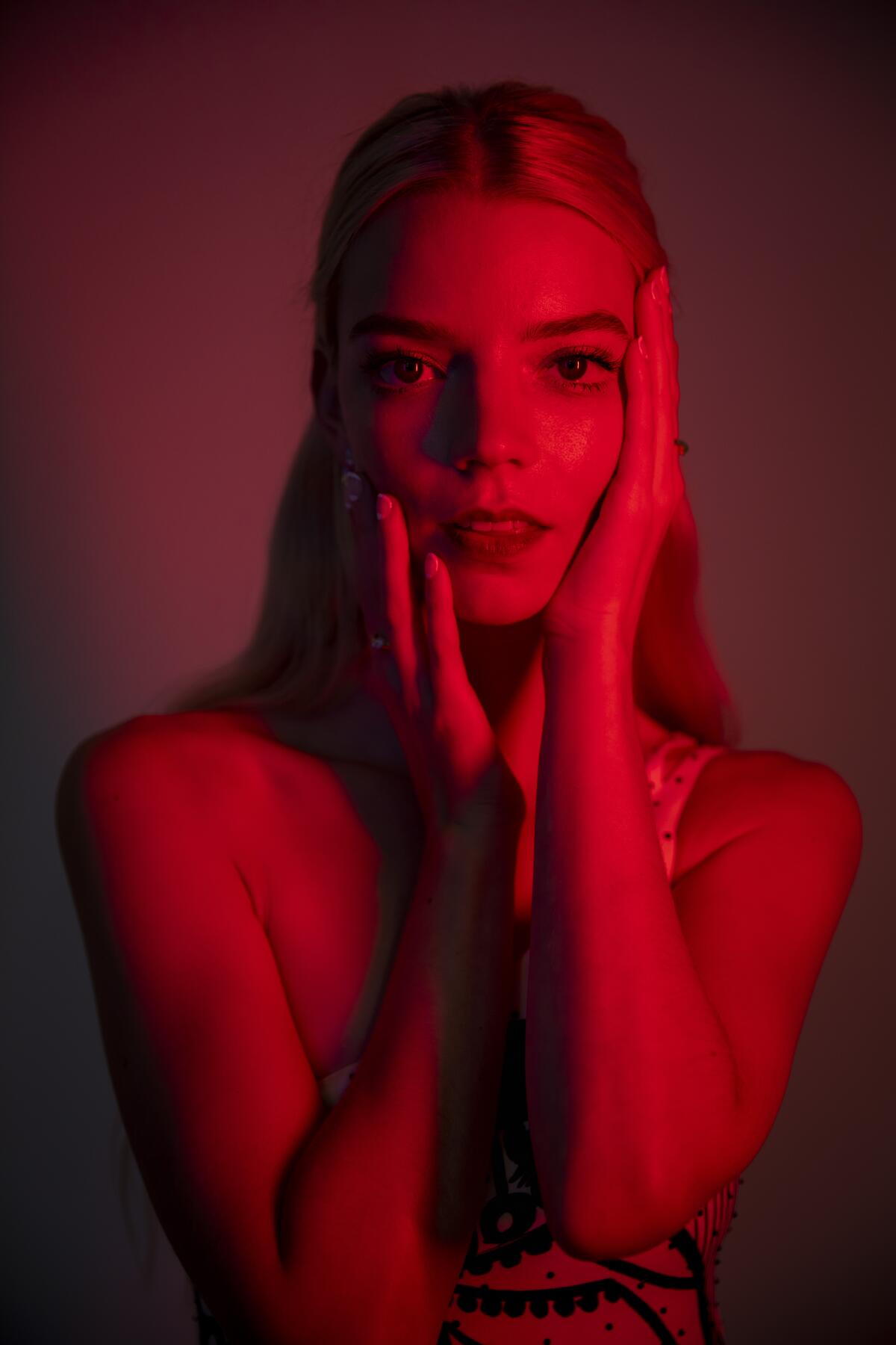 A portrait of Anya Taylor-Joy tinted in red and purple lighting. 