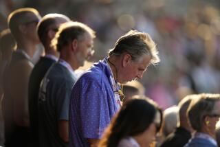 Fans bow their heads during a prayer for former President Donald Trump before an IndyCar auto race, Saturday, July 13, 2024, at Iowa Speedway in Newton, Iowa. (AP Photo/Charlie Neibergall)