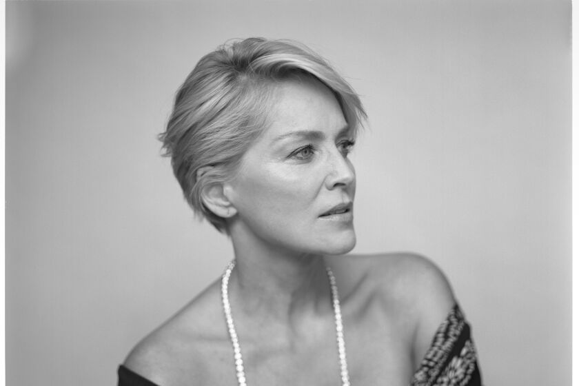 A large-format, black-and-white photo of actor Sharon Stone, waist up, looking pensive.
