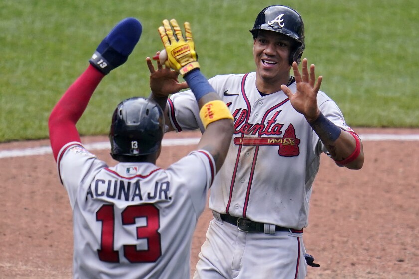 Atlanta Braves' Ehire Adrianza, right, celebrates with Ronald Acuna Jr. after both scored on an RBI single by Orlando Arcia off Pittsburgh Pirates relief pitcher Chasen Shreve during the sixth inning of a baseball game in Pittsburgh, Wednesday, July 7, 2021. (AP Photo/Gene J. Puskar)